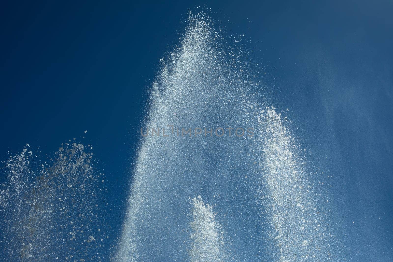 Jets of water against sky. Fountain in city. Details of fountain on street. Splash drops.
