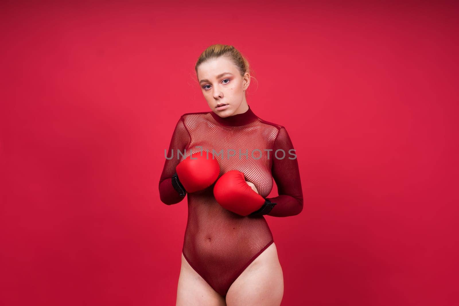 Seductive young and fit female fighter posing in gloves in a studio