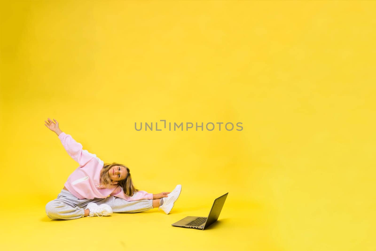 Little blonde kid girl on a pastel yellow wall background. Childhood lifestyle concept.