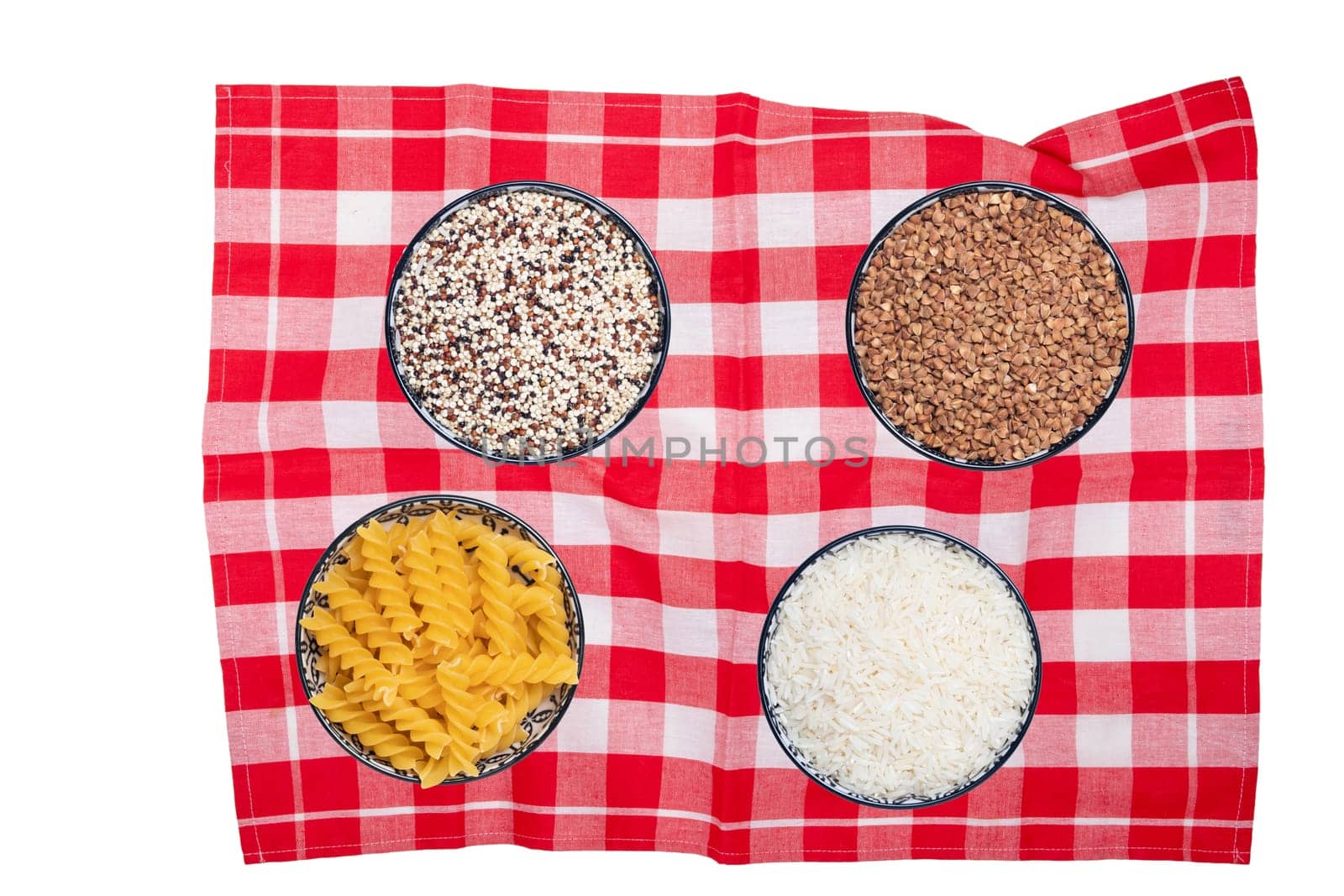 Vegetable food. Closeup of four bowls with buckwheat, noodles, rice and quinoa on a red checkered tablecloth isolated. Healthy eating and nutrition. Top view with space.