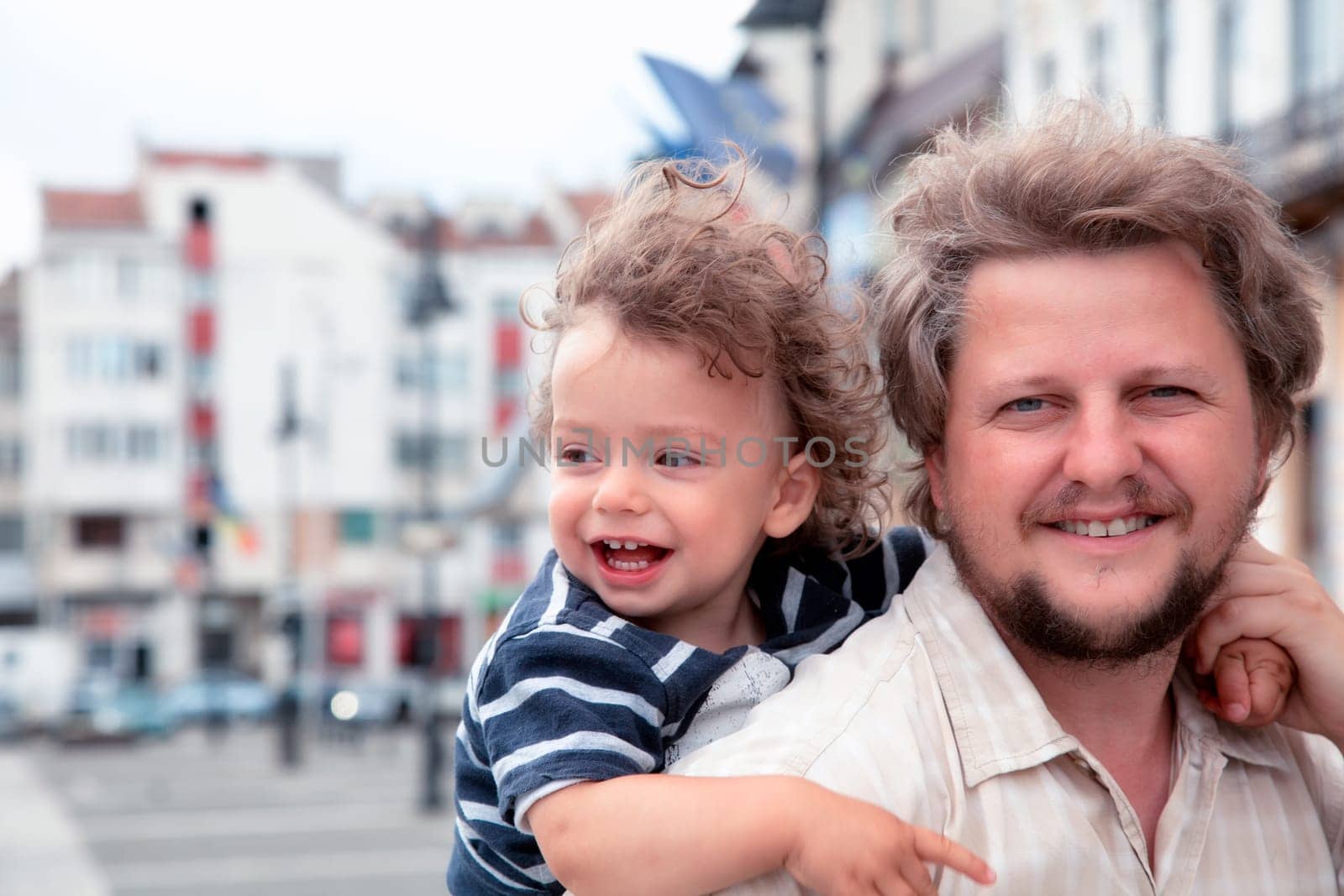 1 year old baby boy laughing while in daddy's back.