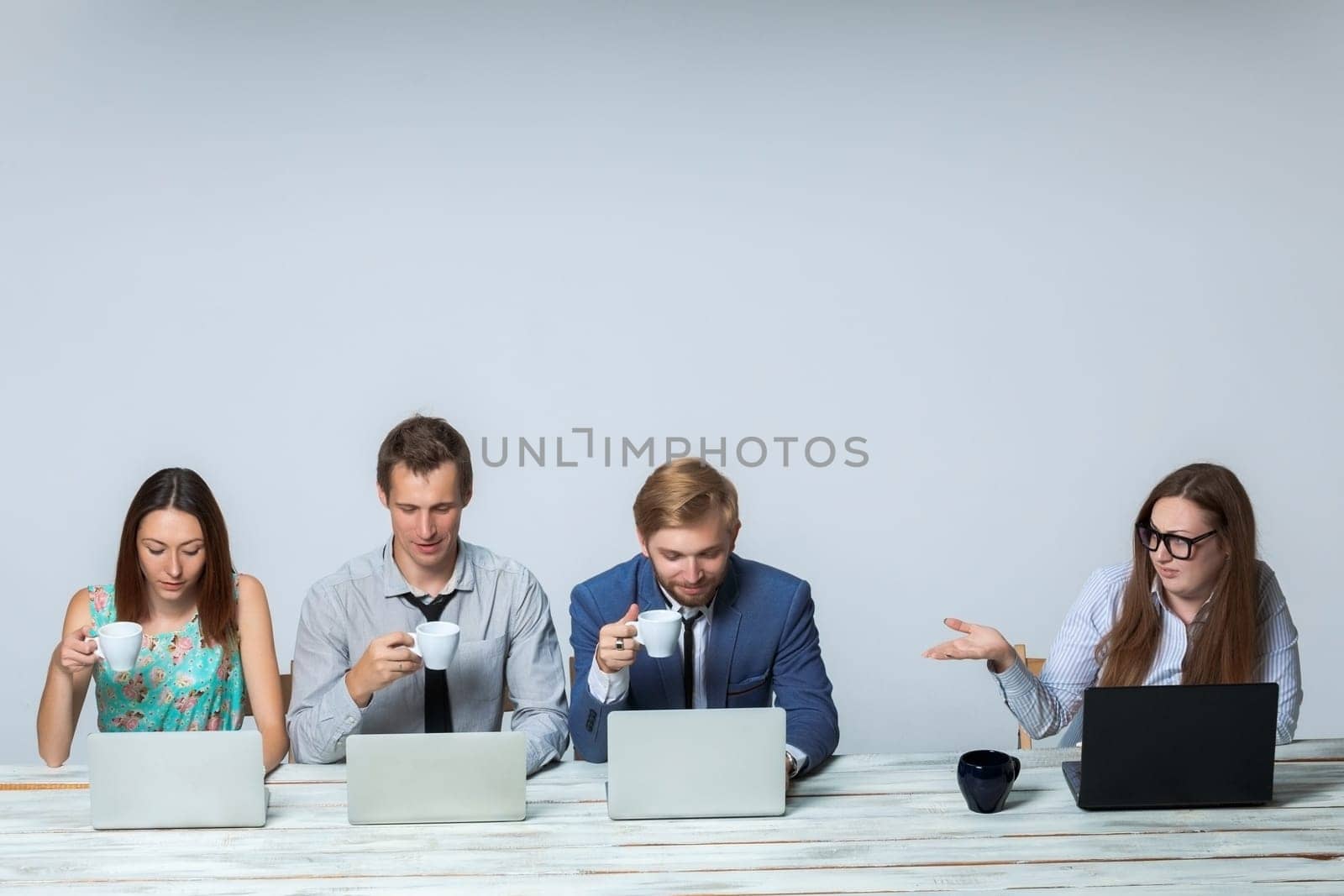 Business team working together at office on light gray background. boss is dissatisfied with the others drinking tea. copyspace image