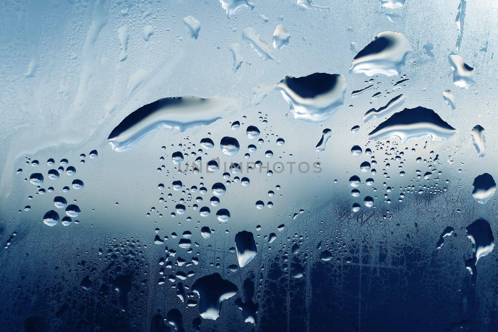 Large and fine water drops on glass background