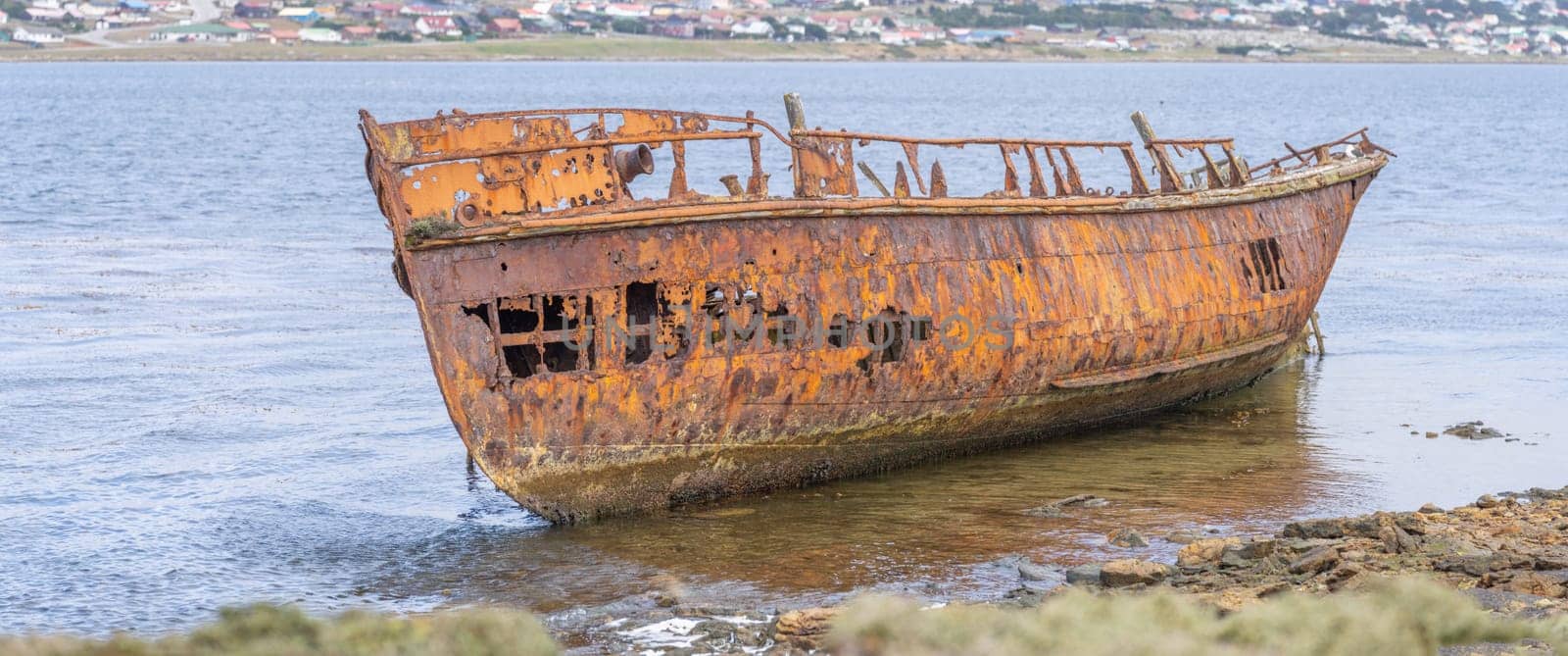 An old whaler wreck in Whalebone Cove off Stanley in the Falkland Islands. Stanley in the background