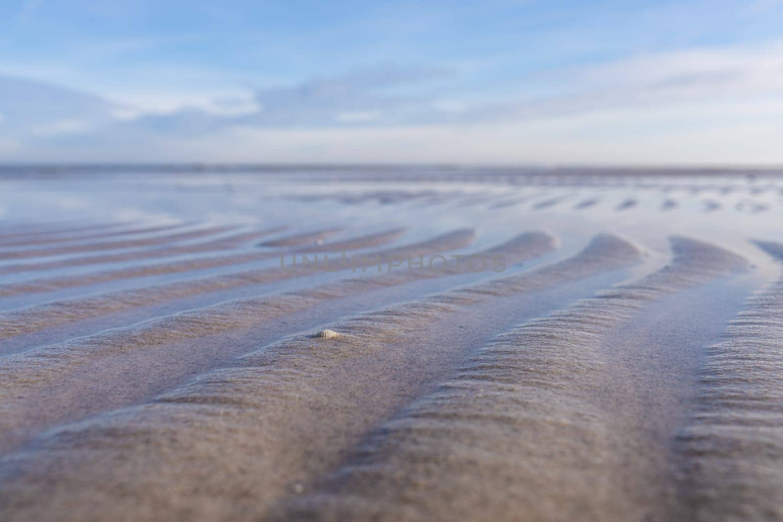 Wave-like patterns in the shallows on the shore of the Baltic Sea against a blue sky. A breathtaking natural phenomenon captured in one photo