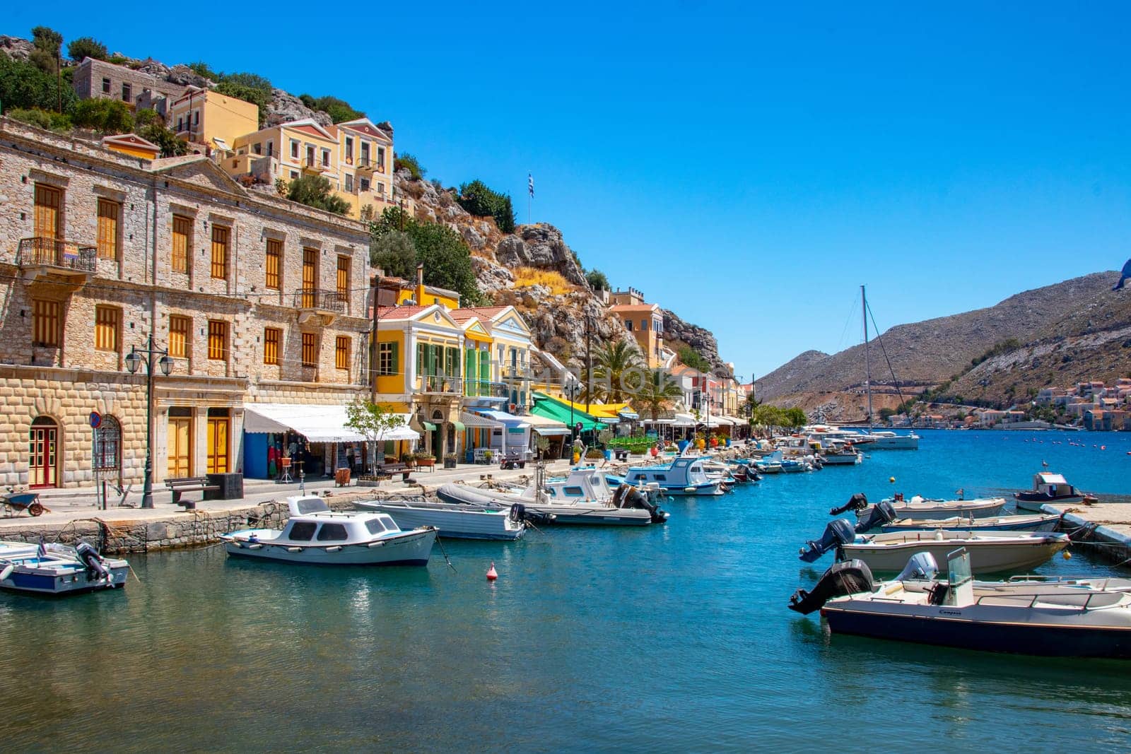 SYMI, Greece - Jun 03, 2021. The harbour of Symi town with the districts of Chorio and Gialos is one of the most beautiful and romantic in the whole Aegean. Colourful mansions stretch up the steep slopes.