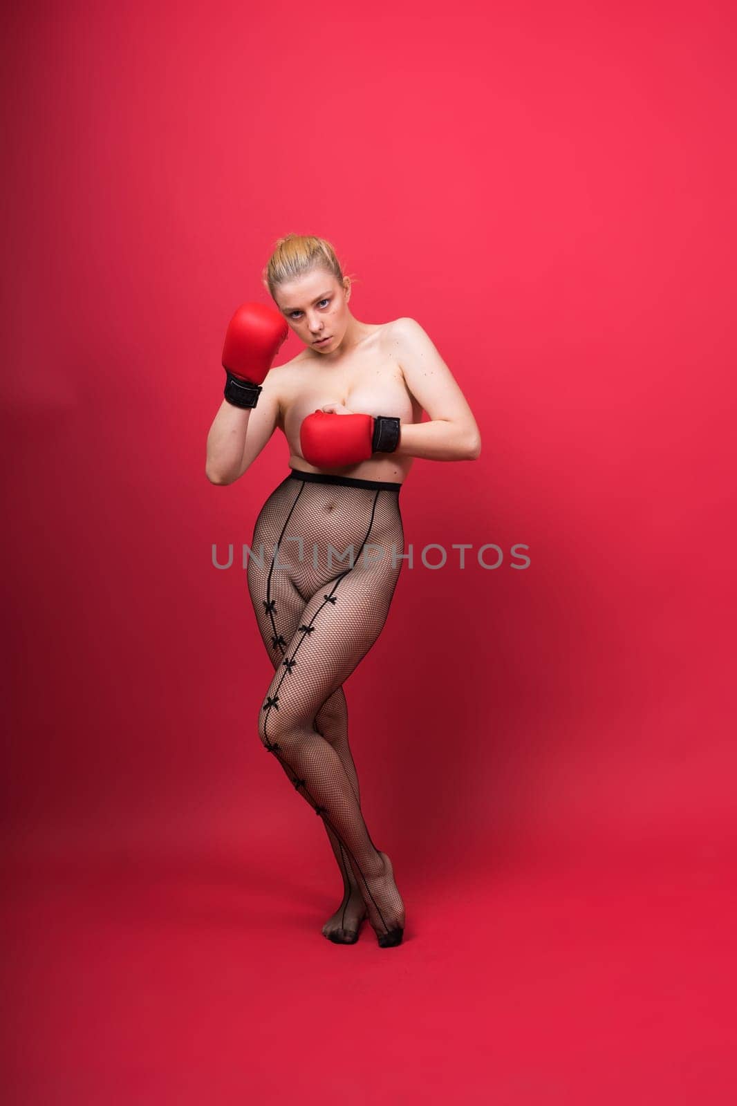 Seductive young and fit female fighter posing in gloves in a studio