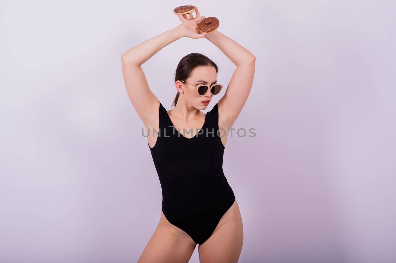 Close up shot of nude woman's body with chocolate covered donuts