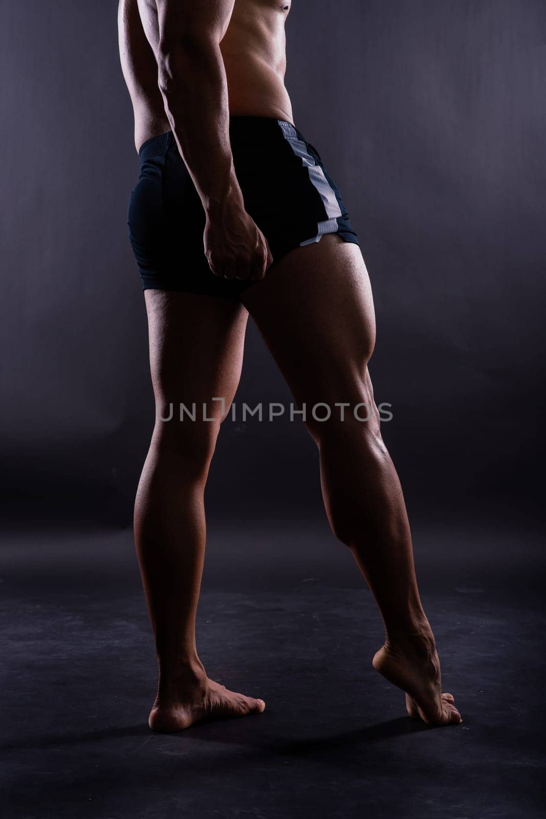 Muscular male legs close up studio shot on dark background