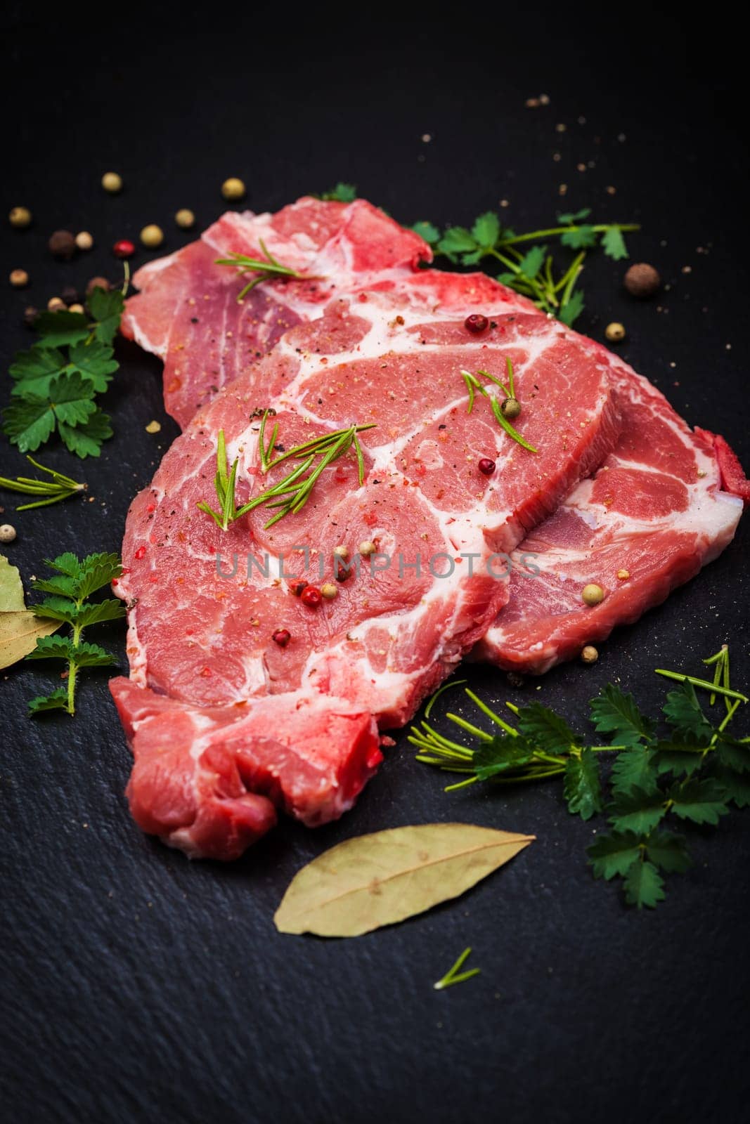 Fresh raw meat on black board with spices and herbs