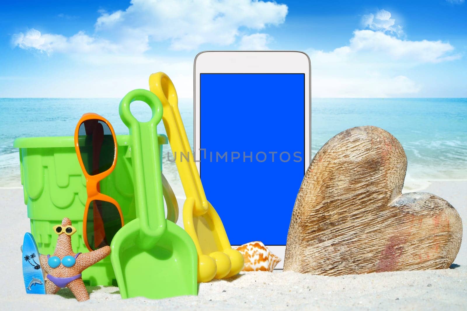 White smartphone,sunglasses and spiezeug on the beach