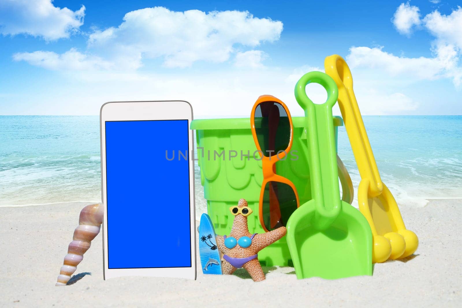 White smartphone,sunglasses and spiezeug on the beach