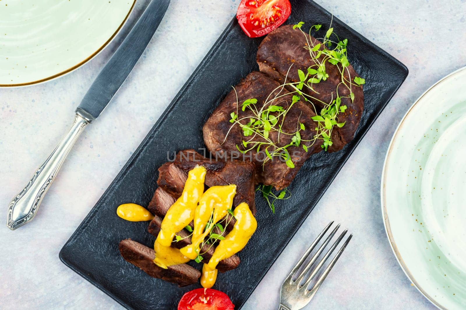 Delicious grilled ostrich meat steaks with microgreens. African cuisine.