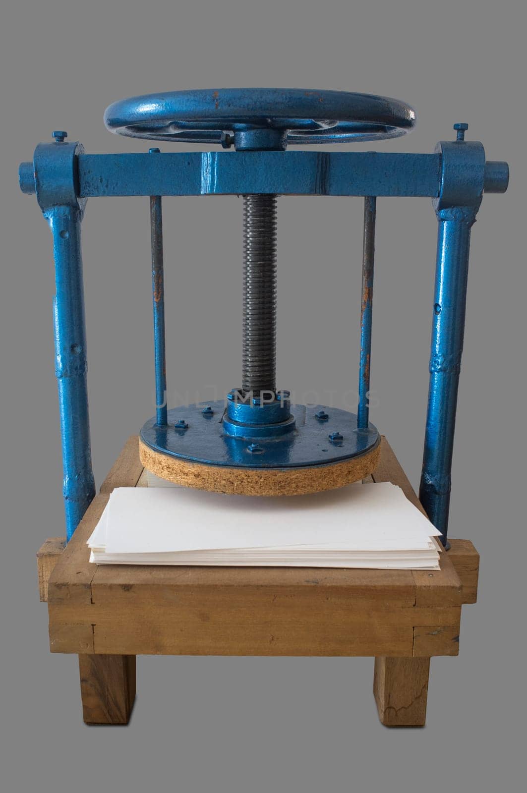 Screw bookbinding press over wooden stand. Isolated over grey background