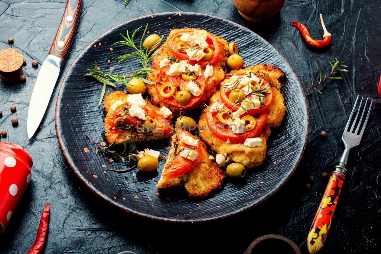 Chicken chops with tomato, olives and cheese. Rustic style