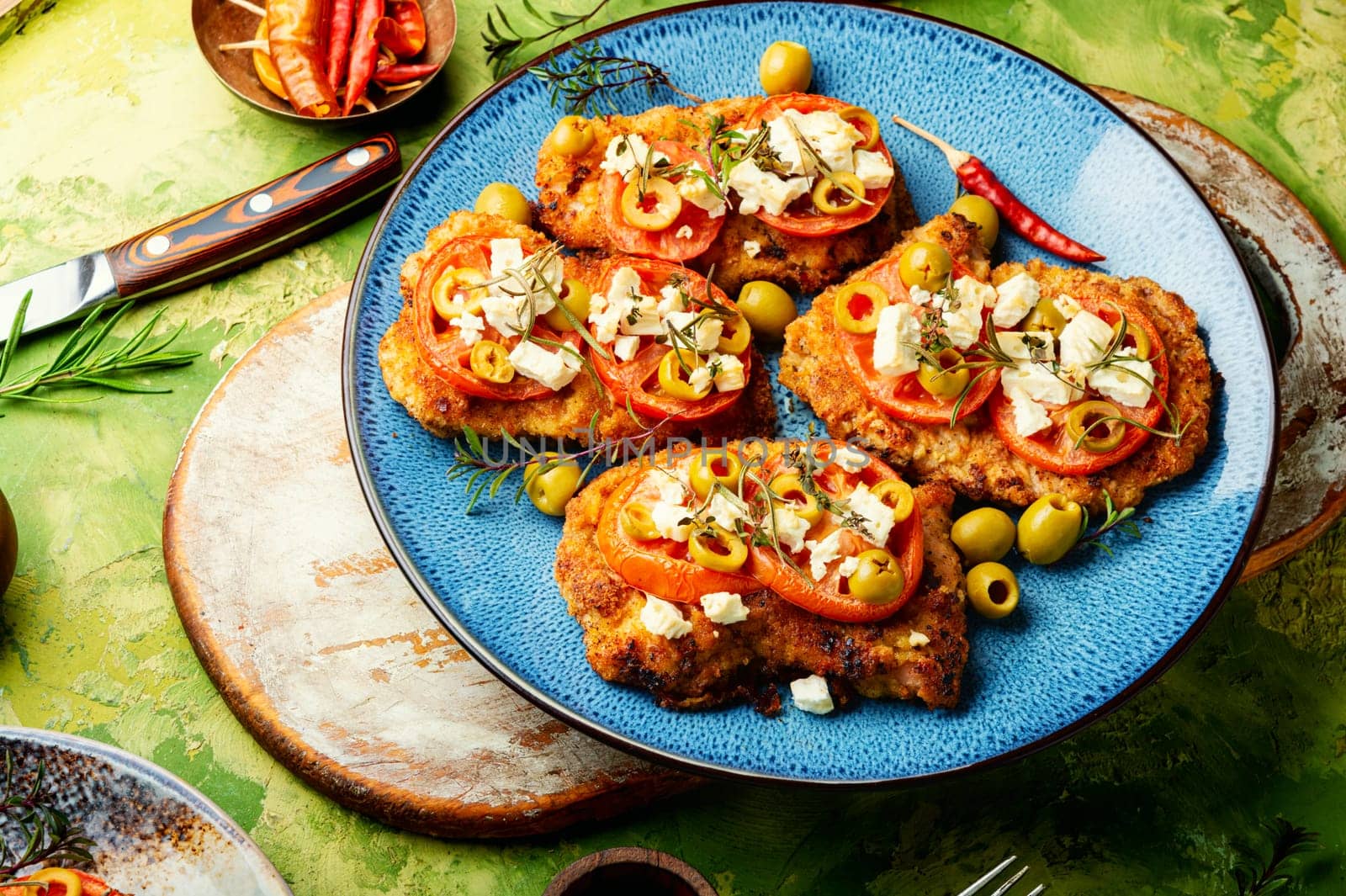 Chicken chops with tomato, olives and cheese. Rustic style