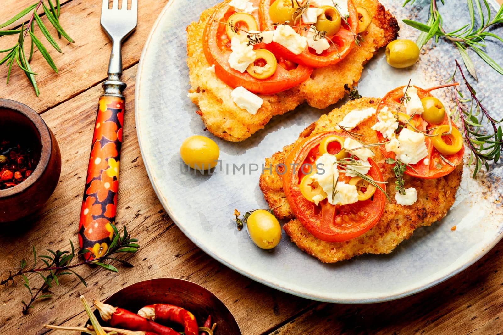 Chicken chops with tomato, olives and cheese. Rustic style