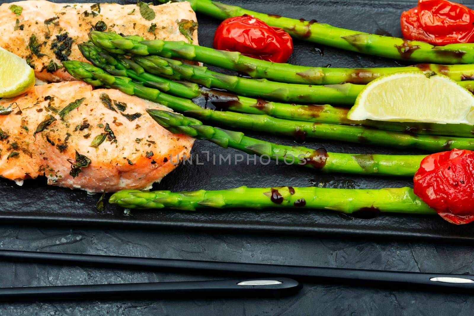 Tasty dish of trout, asparagus and tomato. Baked salmon. Space for text.