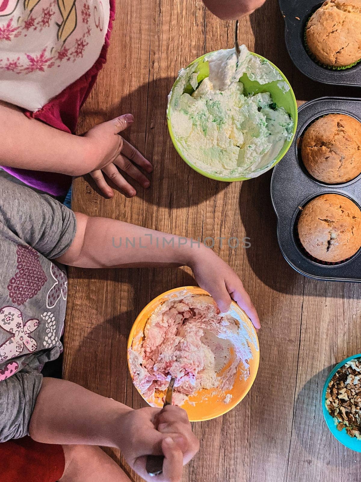 Group of children baking cupcakes, preparing ingredients, toppings, sprinkles for decorating cookies. Kids learning to cook, working together in kitchen at home. Concept of happy family