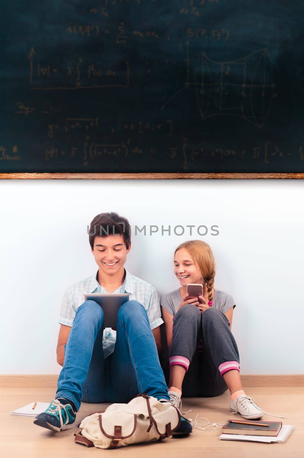Teenagers learning in a classroom sitting by a blackboard on a floor