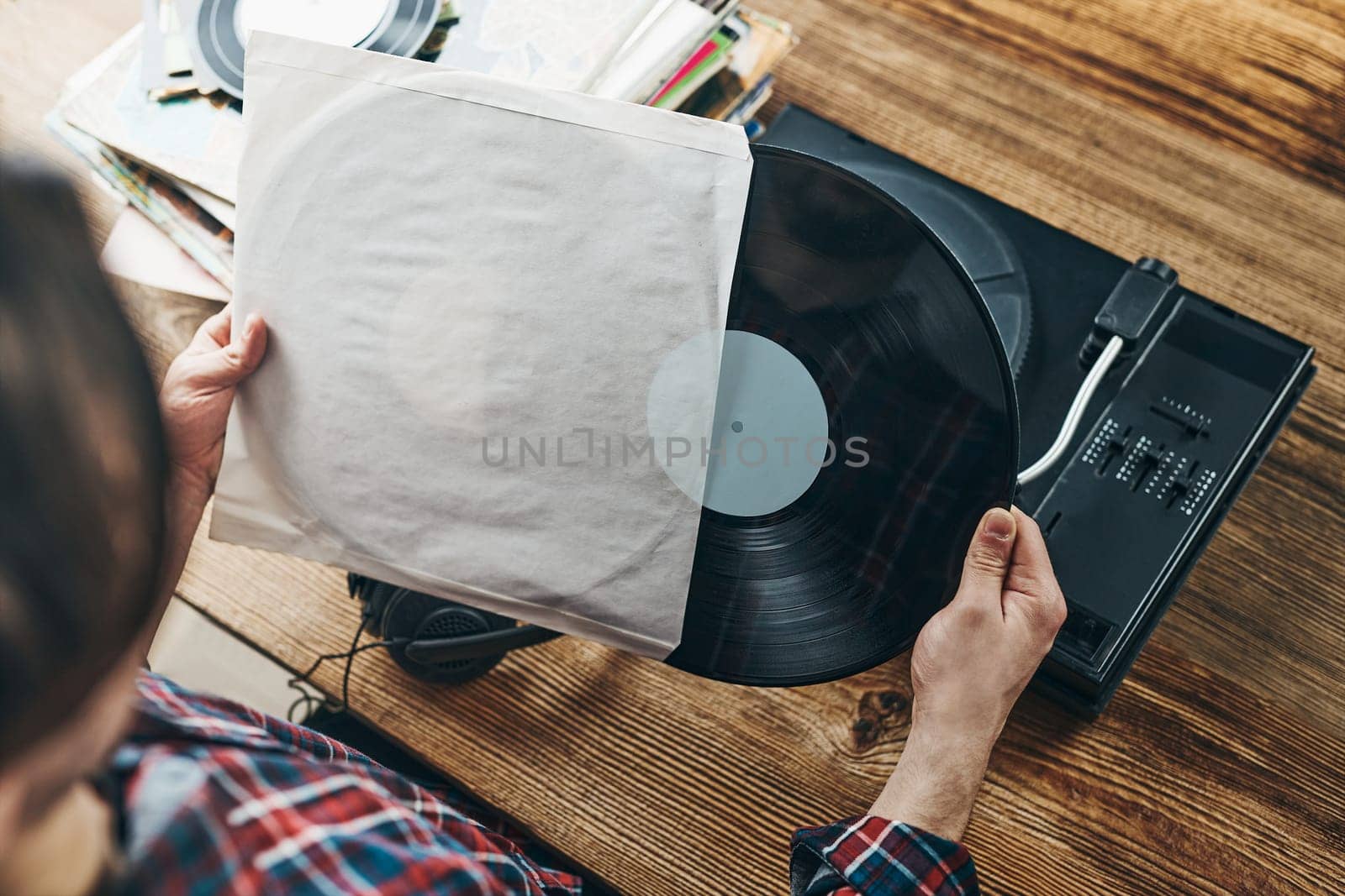 Man listening to music from vinyl record. Playing music from analog disk on turntable player. Enjoying music from old collection. Relaxing at home. Retro and vintage. Music passion