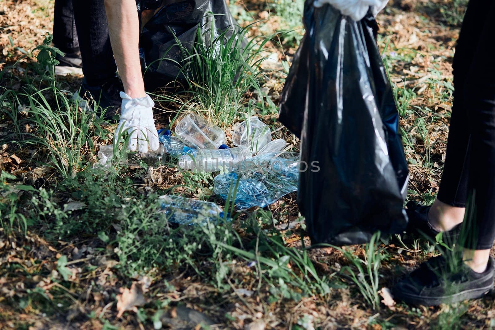 Young man and woman cleaning up a forest. Volunteers picking plastic waste to bags. Concept of plastic pollution and too many plastic waste. Environmental issue. Environmental damage. Responsibility for environment. Real people, authentic situations