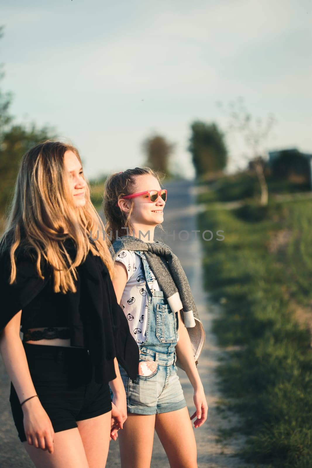 Teenage smiling happy girls having fun walking outdoors, hanging, spending time together on summer day