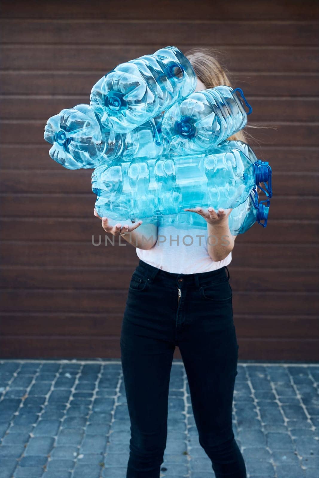 Young woman throwing out empty used plastic water bottles into trash bin. Collecting plastic waste to recycling. Concept of plastic pollution and too many plastic waste. Environmental issue