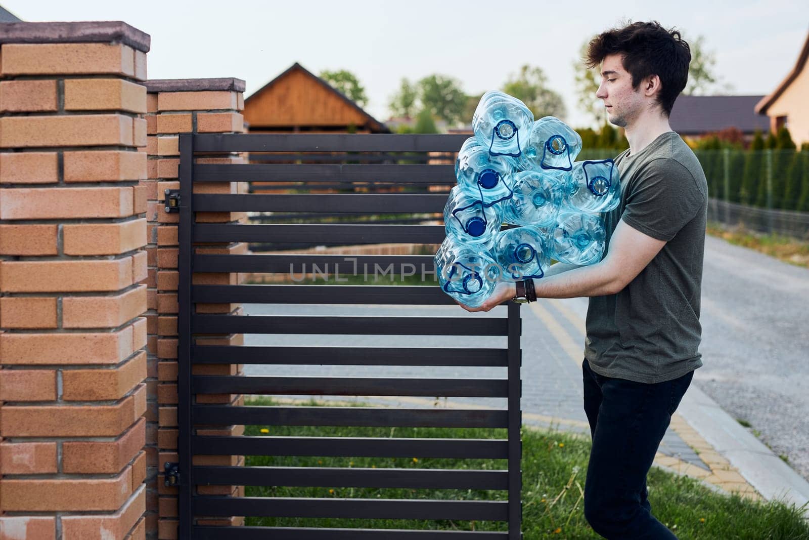 Young man throwing out empty used plastic water bottles into trash bin. Collecting plastic waste to recycling. Concept of plastic pollution and too many plastic waste. Environmental issue