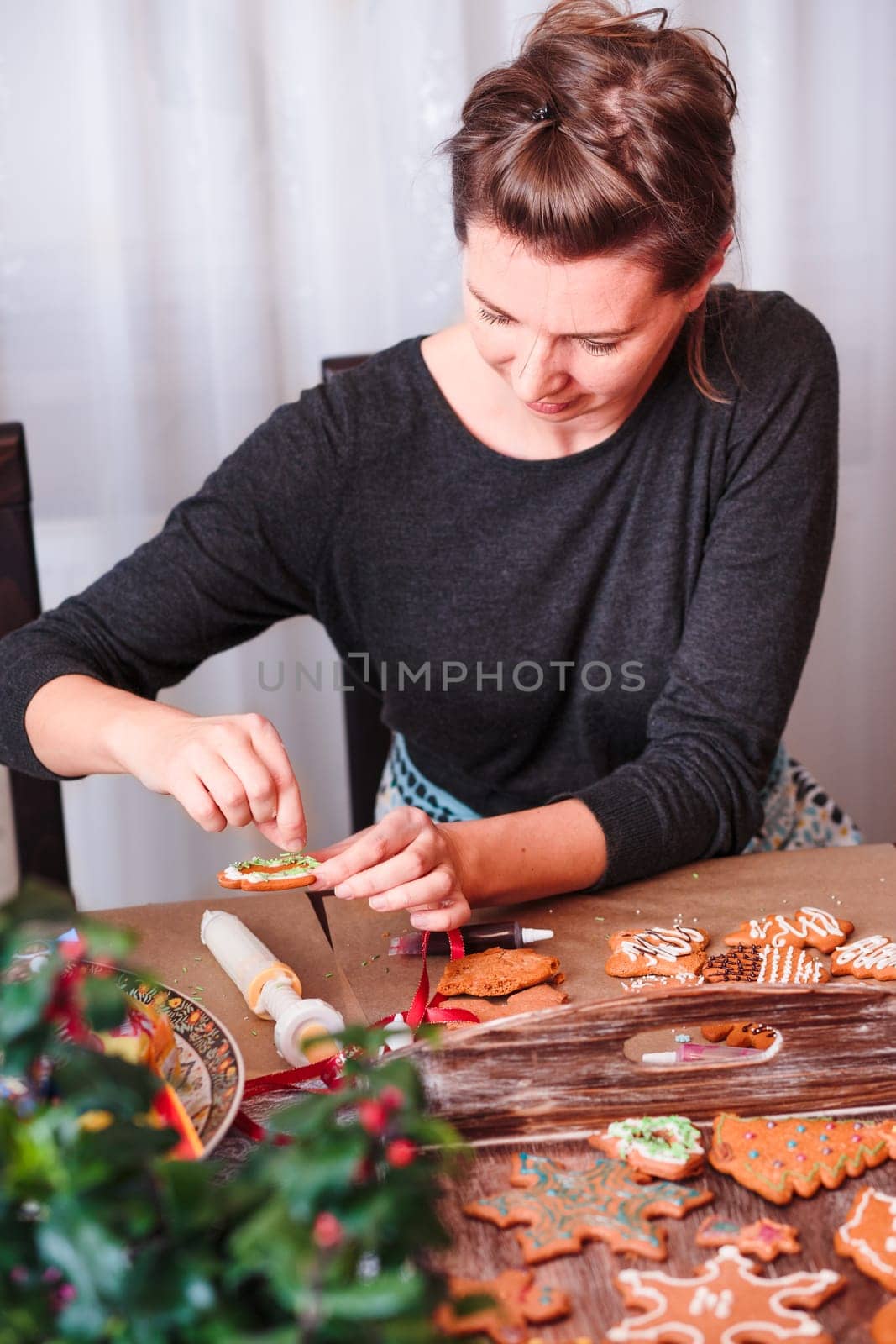 Woman decorating baked Christmas gingerbread with frosting