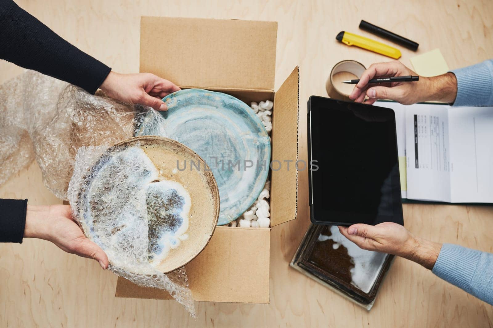 Business owner packing online order to delivery to customer. Preparing parcel box with ceramic plate product from online shop