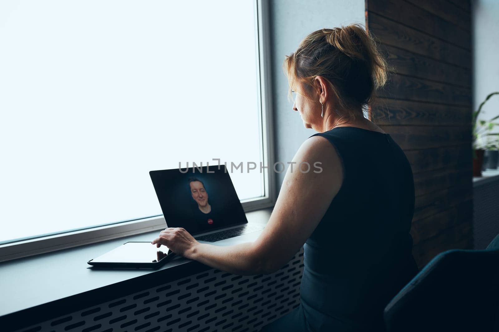 Businesswoman having business video call on laptop in office. Mature busy woman remotely working from office. Female manager using digital devices. Remote communication. Video calling. Remote work