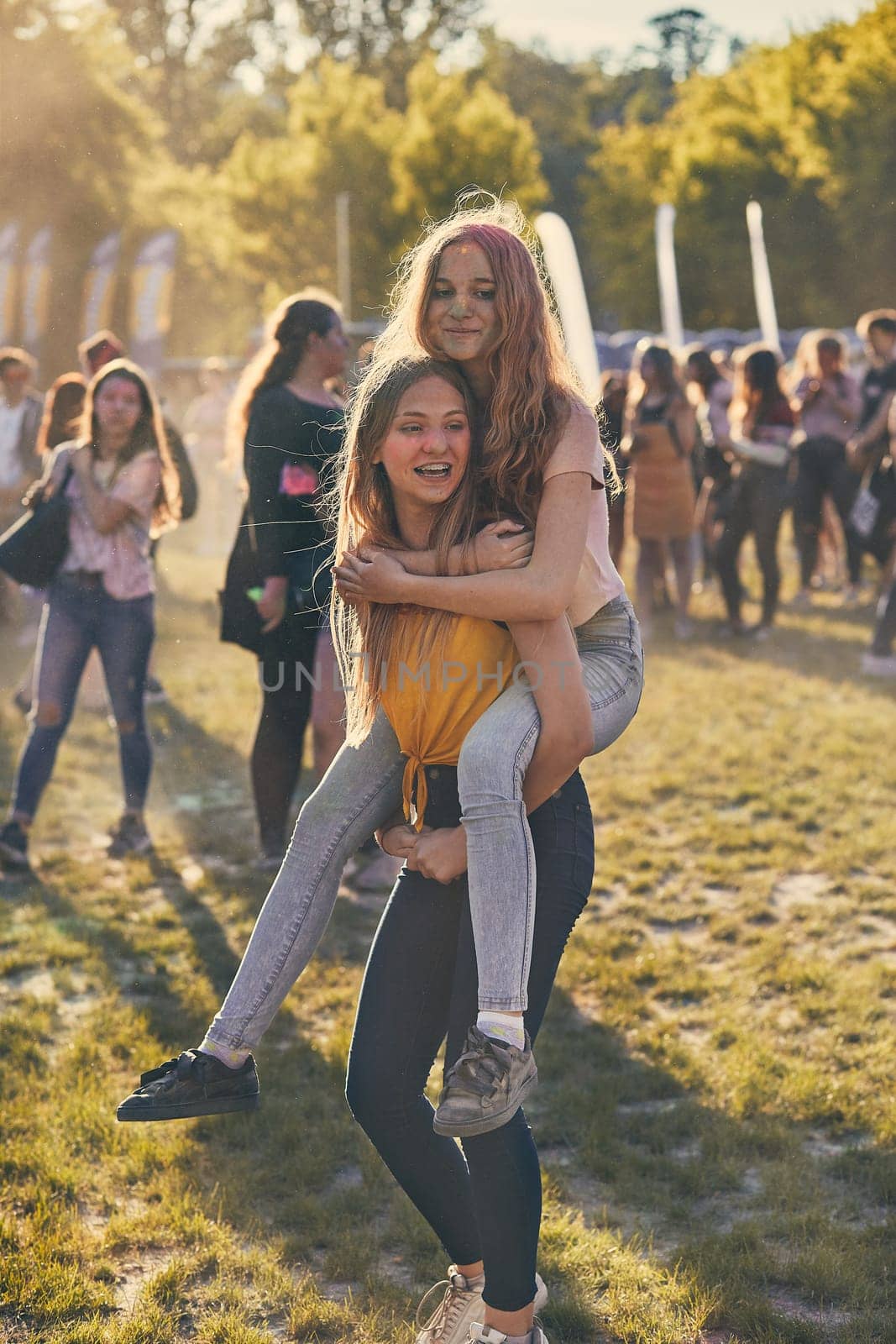 Portrait of happy smiling young girls with colorful paints on faces and clothes. Two friends spending time on holi color festival