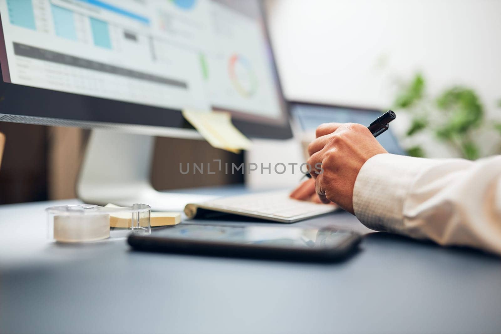 Woman entrepreneur working with data on charts, graphs and diagrams on computer and smartphone. Woman sitting at desk in office