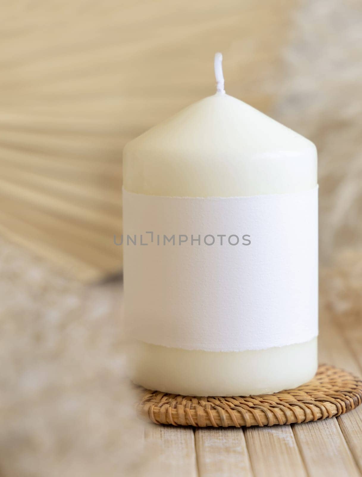 Candle with blank paper label on wooden table with dried pampas grass, Close up, copy space. Minimal brand packaging mock up. Home decoration, minimal interior, Bohemian or scandinavian style