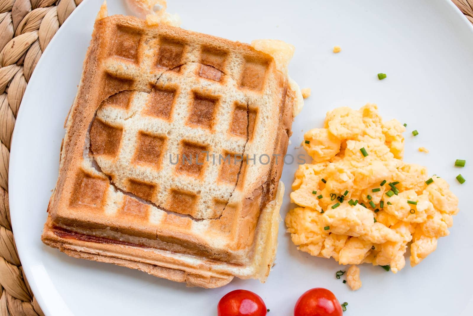 Delicious toast sandwich with eggs and cherry tomatoes on white plate.