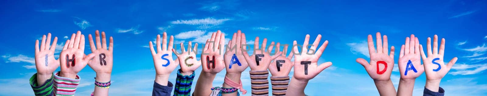 Children Hands Building Colorful German Word Ihr Schafft Das Means You Can Do It. Blue Sky As Background.