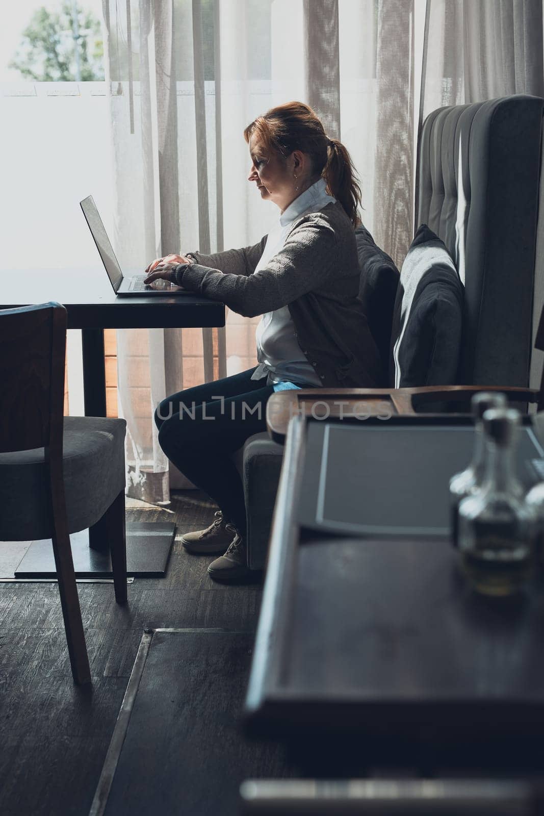 Focused businesswoman working remotely on her laptop computer contemplate managing her work sitting at the table in a cafe