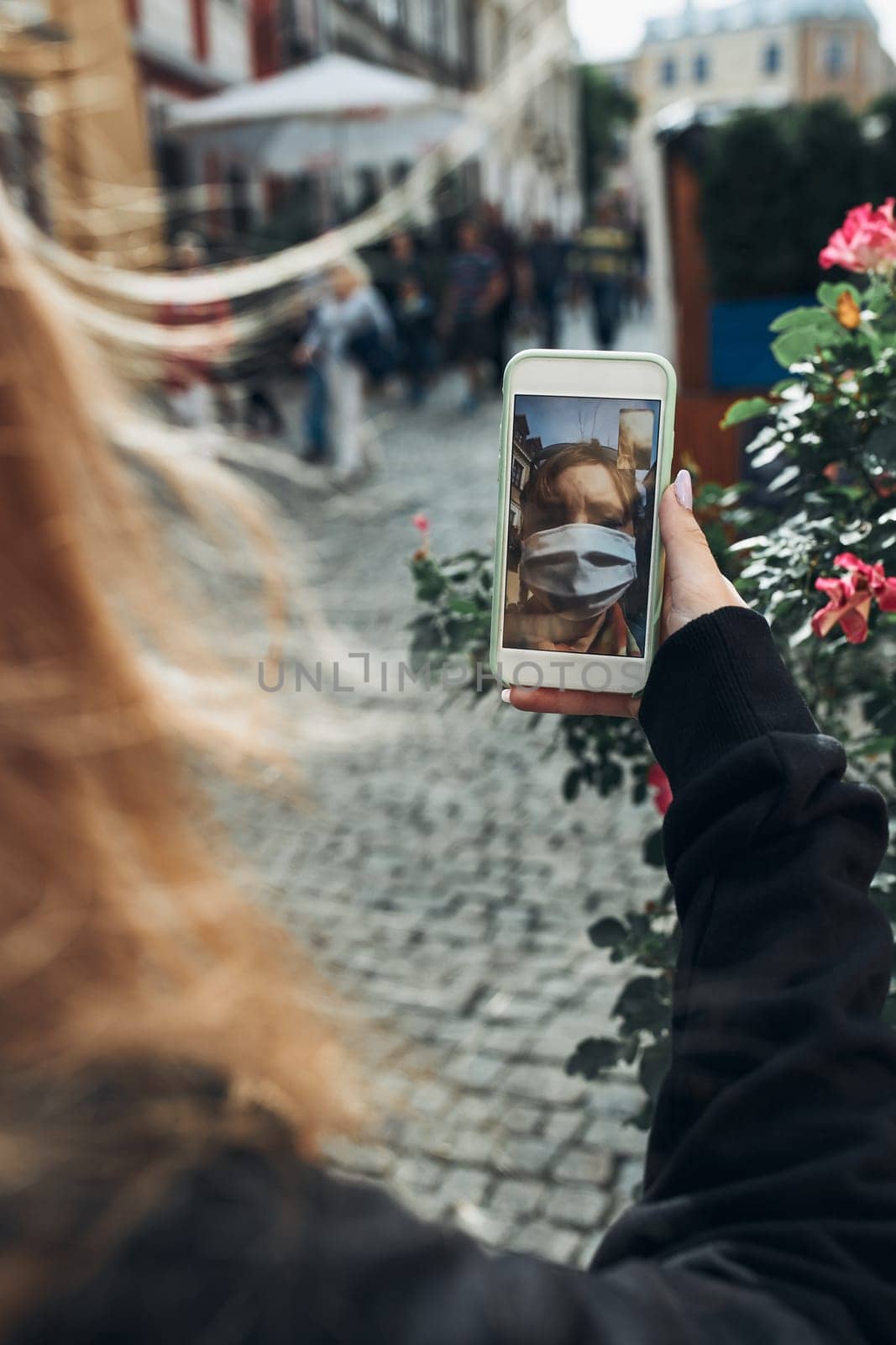 Young woman having video call talking while walking downtown in the evening wearing the face mask to avoid virus infection and to prevent the spread of disease in time of coronavirus