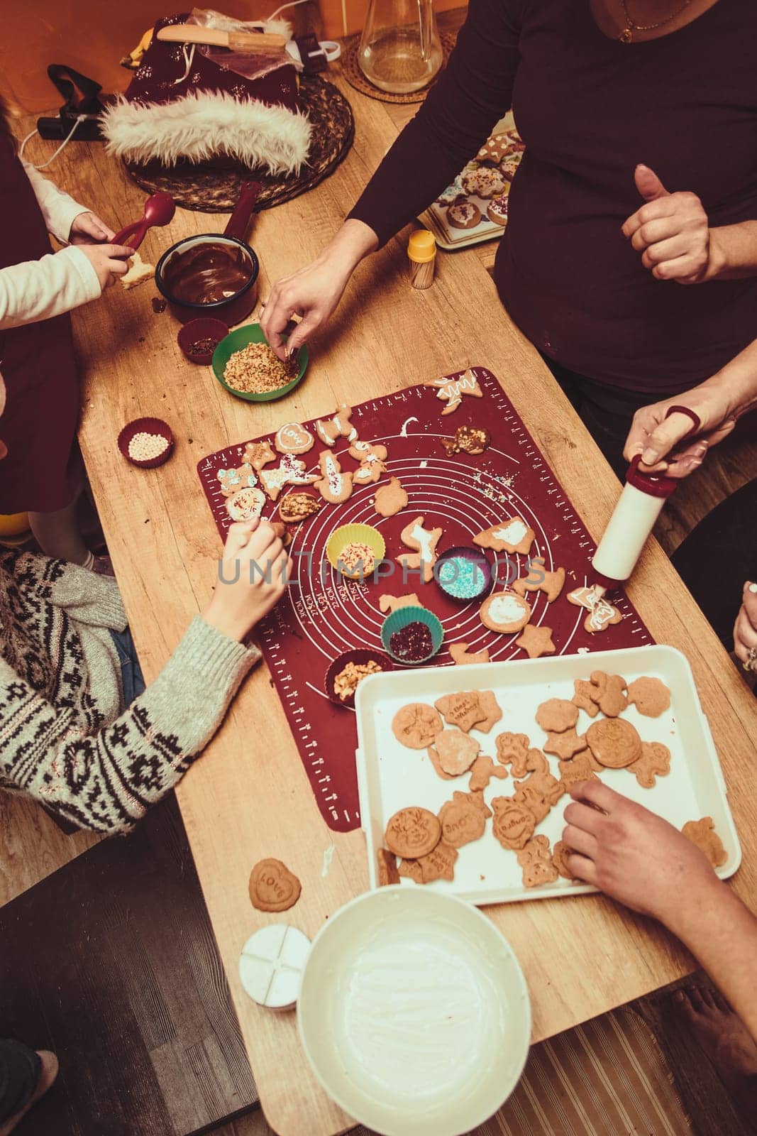 Baking Christmas cookies. Christmas gingerbread cookies in many shapes decorated with colorful frosting, sprinkle, icing, chocolate coating, toppers, put on table. Baking traditional cookies. Family celebrating Christmas. Baking at home. Baked sweet cookies. Coating with frostings. Colouring cookies. Decorating baked cookies. Decoration and design of food. Flat top-down composition. Sweet dessert food. Putting a frost, frosting gingerbread. Shot from above