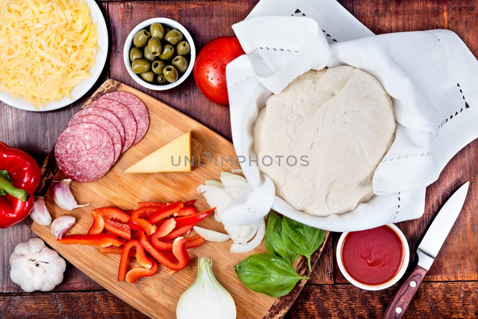 Ingredients, cheese, vegetables prepared for homemade pizza, on wooden board on the table. View from above