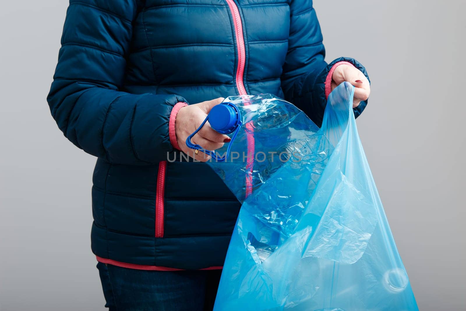 Woman throwing out used plastic bottles and packagings in trash bin. Collecting empty plastic squashed bottles in blue bag. Plastic waste to recycling. Concept of plastic pollution and too many plastic waste