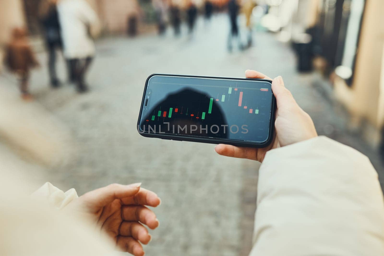 Person investing trading on stock cryptocurrency market using investing application on smartphone. Stock market investment in hand. Trader holding mobile phone looking at candle chart