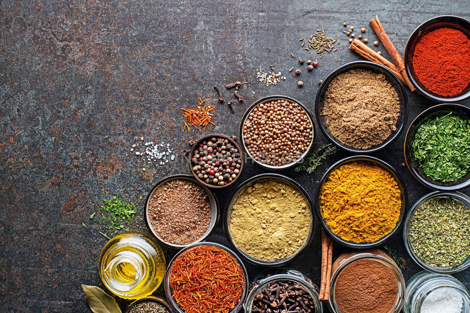 Colorful herbs and spices for cooking meal. Indian and Asian spices On grey stone background. Top view.