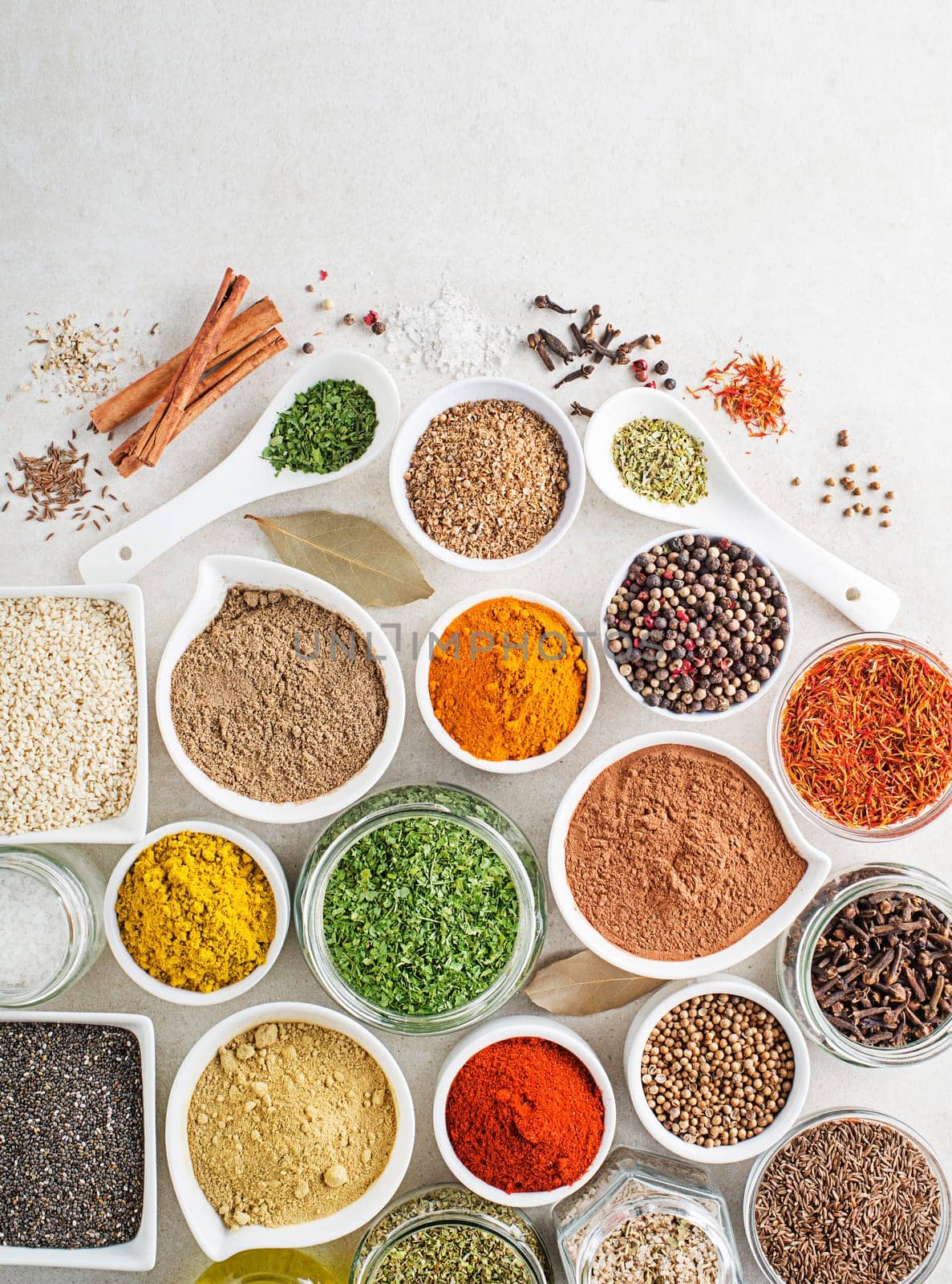 Colorful herbs and spices for cooking dishes. Indian and asian spices on white stone background. Top view.
