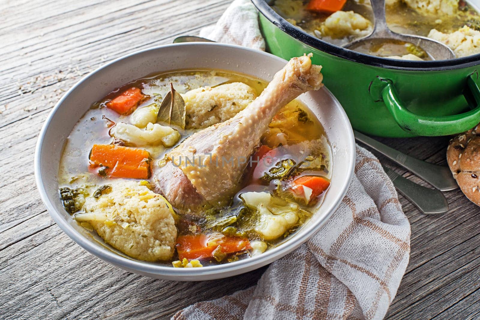 Fresh chicken soup with vegetable and semolina dumplings on wooden table close up