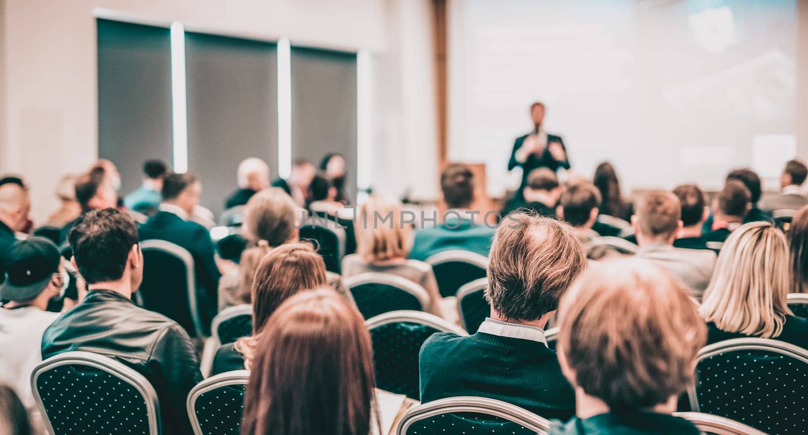 Speaker giving a talk in conference hall at business event. Rear view of unrecognizable people in audience at the conference hall. Business and entrepreneurship concept