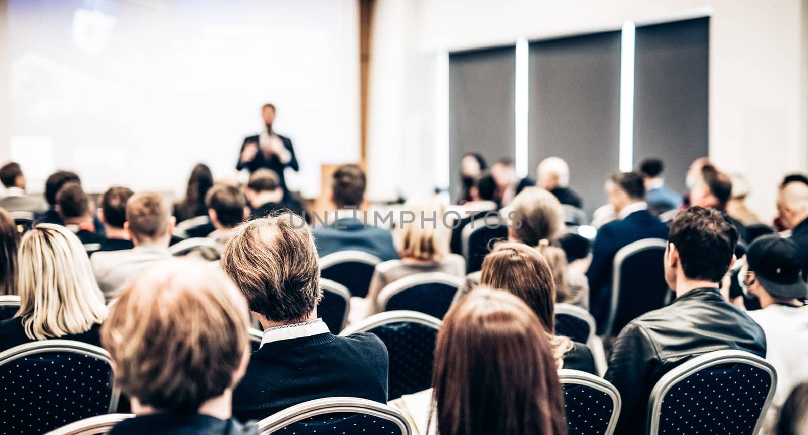 Speaker giving a talk in conference hall at business event. Rear view of unrecognizable people in audience at the conference hall. Business and entrepreneurship concept