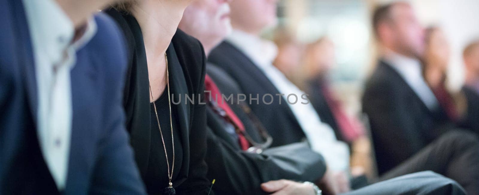 Row of unrecognizable business people sitting in conference hall at business event. Audience at business seminar. Business and Entrepreneurship concept.