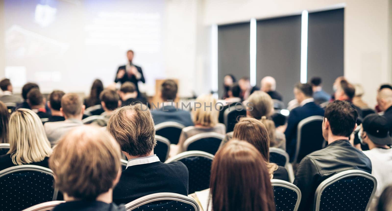 Speaker giving a talk in conference hall at business event. Rear view of unrecognizable people in audience at the conference hall. Business and entrepreneurship concept